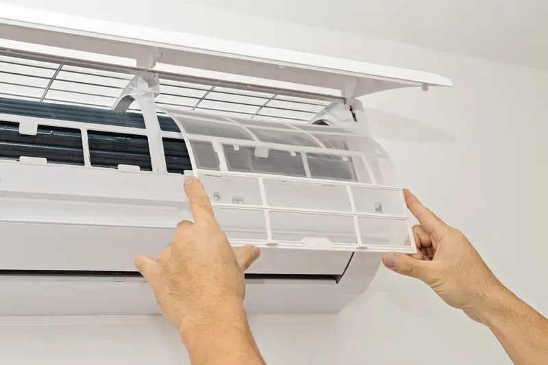 Filter being removed from a split aircon indoor unit for cleaning