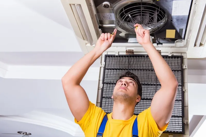 Technician servicing a commercial ceiling cassette unit