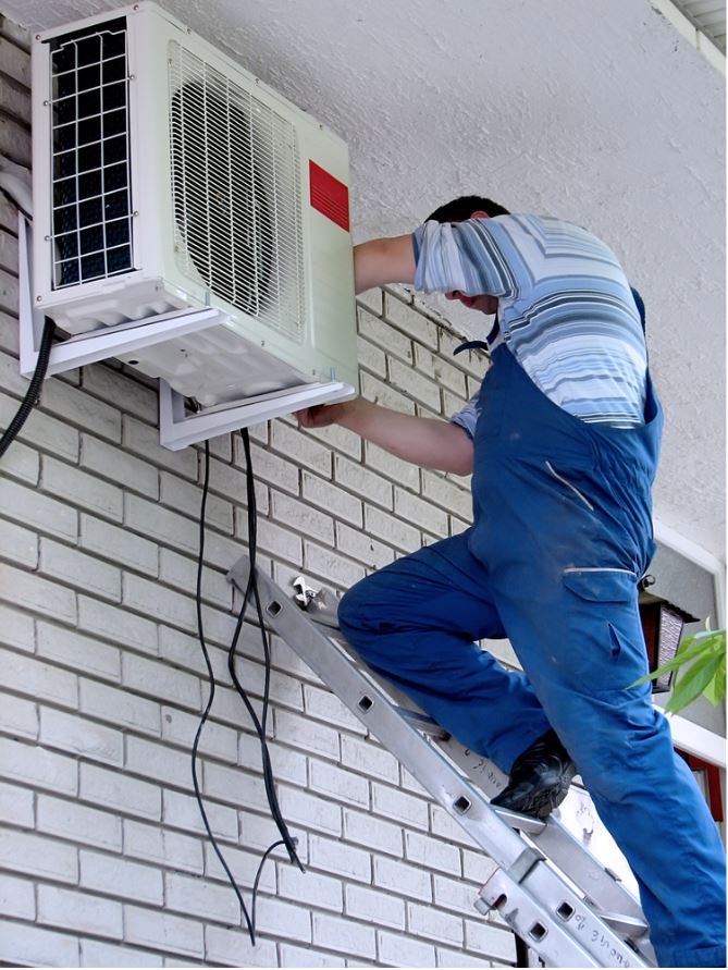 Picture of technician working on the installation of the outside portion of the air conditioning unit