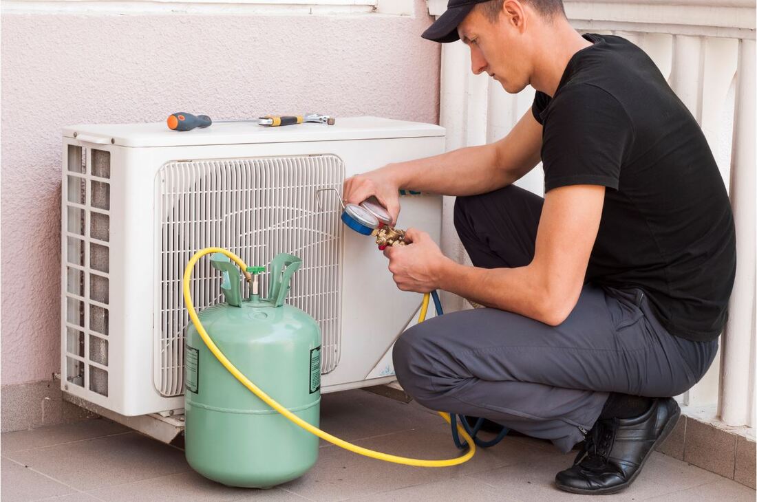 Picture of technician re-gassing and checking outside air conditioning system temperature